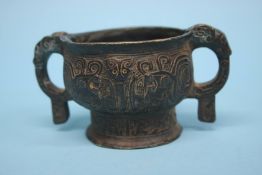 A Chinese antique bronze vessel, with two looped handles and incised decoration. 10cm diameter,