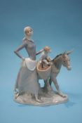 A Lladro group of a mother with her child and donkey collecting water, 34cm wide