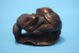 A carved hardwood netsuke in the form of two toads on a lily pad