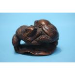 A carved hardwood netsuke in the form of two toads on a lily pad