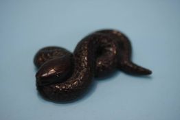 A carved hardwood netsuke in the form of a coiled serpent