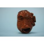 A carved hardwood netsuke in the form of a monkey's head