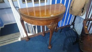 A walnut demi lune fold over card table, with claw and ball feet, 83cm wide