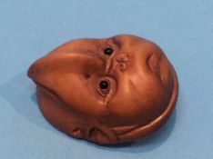 A carved netsuke in the form of a reversable child's face