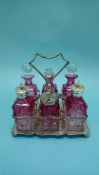 A cranberry and clear glass six bottle cruet with plated stand