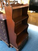 A reproduction mahogany waterfall front open bookcase