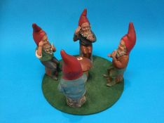 An unusual set of four Continental seated pottery gnomes playing cards, each seated around a central
