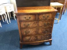 A reproduction walnut bow front chest of drawers