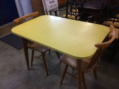 A yellow melamine table and two spindle back chairs