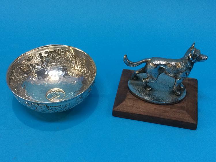 A white metal bowl together with a Desmo car mascot modelled as a German Shepherd