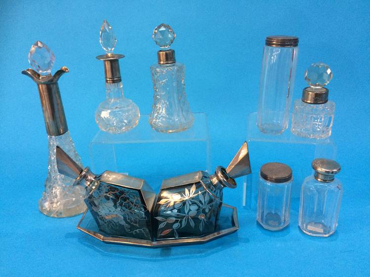 A collection of various silver rimmed and topped scent bottles etc.