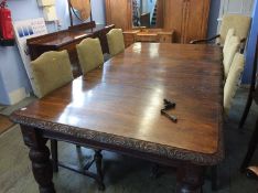 An early 20th century carved oak wind out dining table with carved edge, supported on carved