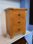 A modern oak bedside chest of drawers