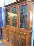 An Edwardian walnut Art Nouveau bookcase, with leaded glass doors and carved panelled doors