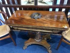 A William IV mahogany fold over tea table with turned and carved central column and lion paw feet