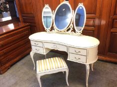 A cream dressing table with mirrors and stool