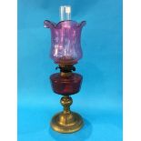 An oil lamp with Cranberry coloured reservoir and etched shade