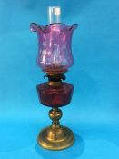 An oil lamp with Cranberry coloured reservoir and etched shade