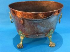 A copper oval log bin with brass handles and lion paw feet