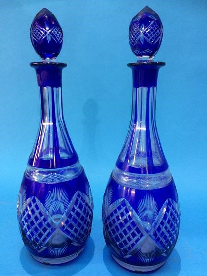 A pair of blue and clear glass flashed hobnail cut decanters