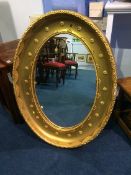 A large gilt oval mirror, 87cm height