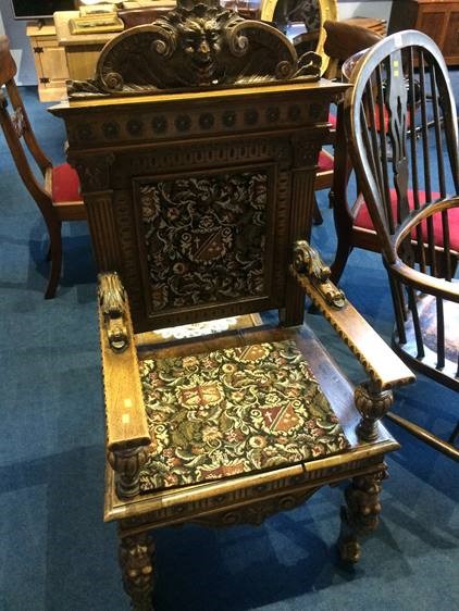 A heavily carved oak hall chair. 54cm width, 125cm high - to top, 68cm high to top of arms