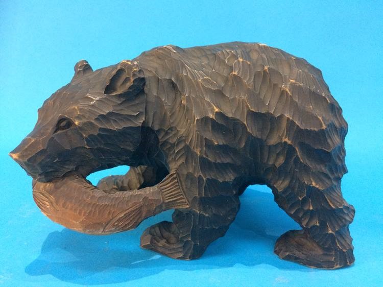 A carved wooden Bear holding a fish in his mouth