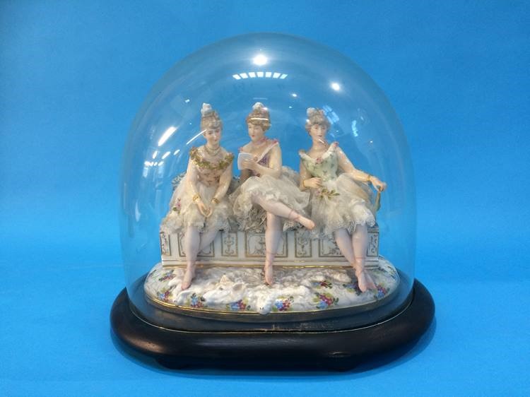 A late 19th century Continental porcelain group of three young Ladies seated on a bench, under a