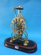 A brass Skeleton clock under a glass dome. 36 cm high