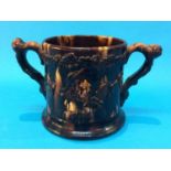 A 19th century two handled 'Frog' Loving cup, decorated with figures and dogs on a brown treacle