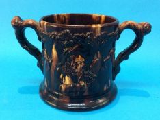 A 19th century two handled 'Frog' Loving cup, decorated with figures and dogs on a brown treacle