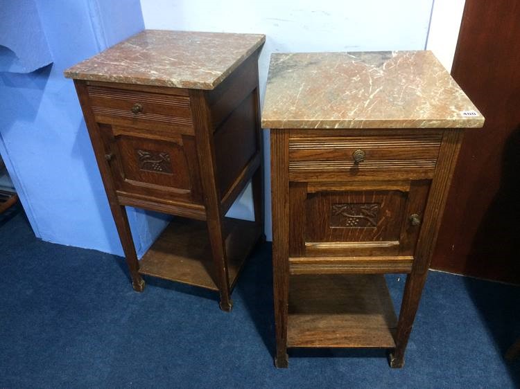 A pair of oak and marble top bedside cupboards