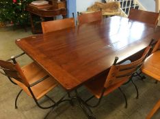 A modern refectory table with six wrought iron and leather chairs