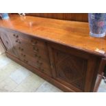 An oak sideboard with five long drawers and two cupboard doors, supported on a plinth base, 183cm