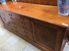 An oak sideboard with five long drawers and two cupboard doors, supported on a plinth base, 183cm