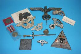 A German Third Reich eagle car mascot, an N.S.K.K. (National Socialist Motor Corps) badge, a