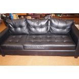 A modern three seat settee in black leather