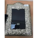 An ornate scroll embossed silver photograph frame