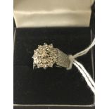 An 18ct diamond cluster ring in wide barked shank