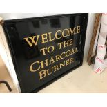 A painted sign: "Welcome to the Charcoal Burner"