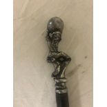 A vintage silver walking cane in the form of a gnome holding a ball above his head with a serpent