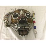 A beaded tribal mask with club and horn