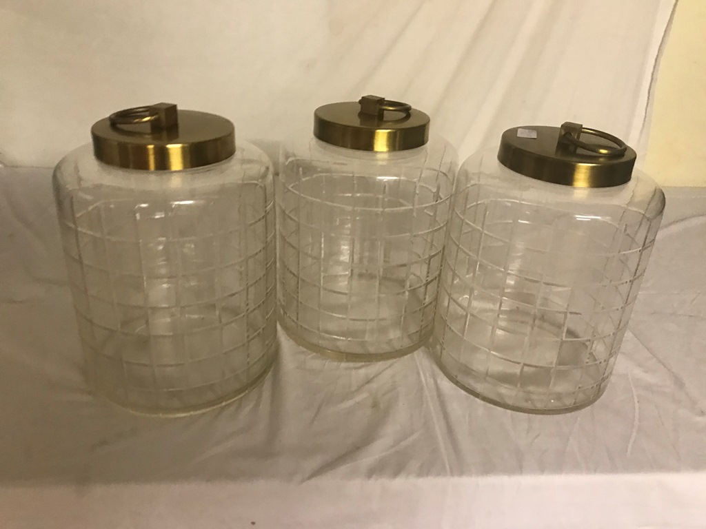 A set of three cut glass cannisters with brass lids