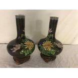 A pair of cloissone vases on wooden stands