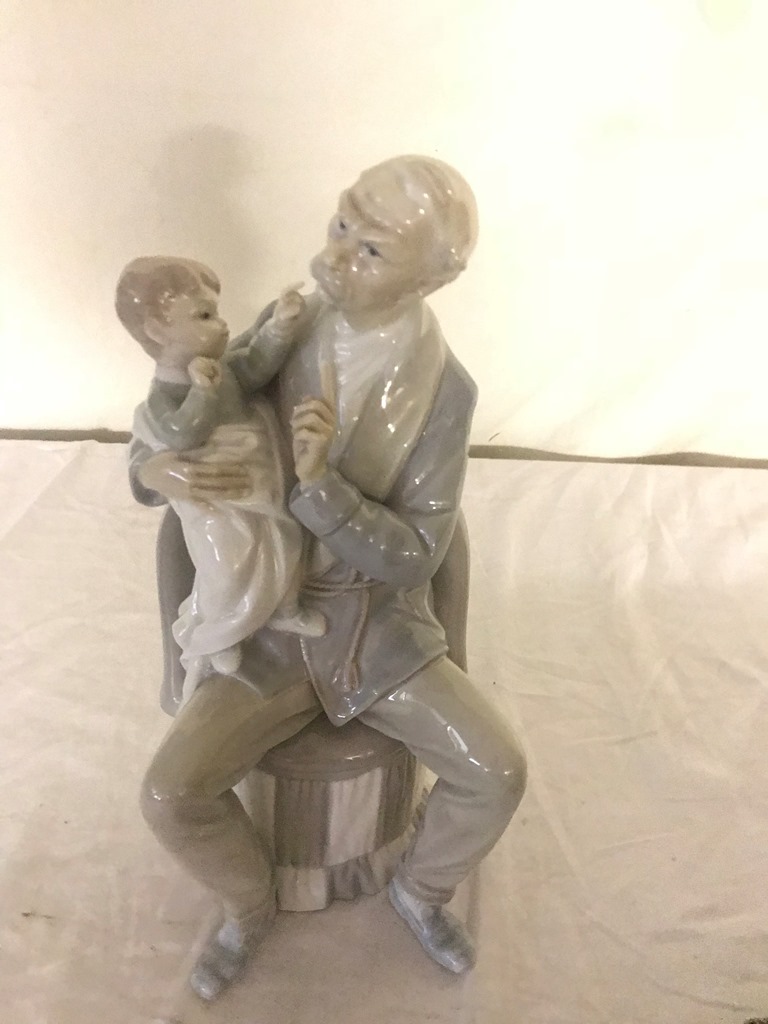 A Lladro figure of a man with a child on his lap