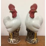 A pair of Chinese Qing Dynasty roosters, on stump bases with glazed white bodies, painted combs,