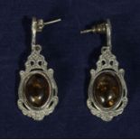 A pair of silver earrings set with amber