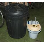 A plastic dustbin containing gardening items and a bucket