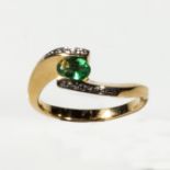 An 18ct gold emerald and diamond cross over ring, size M