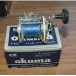 An Okuma fishing reel and one other